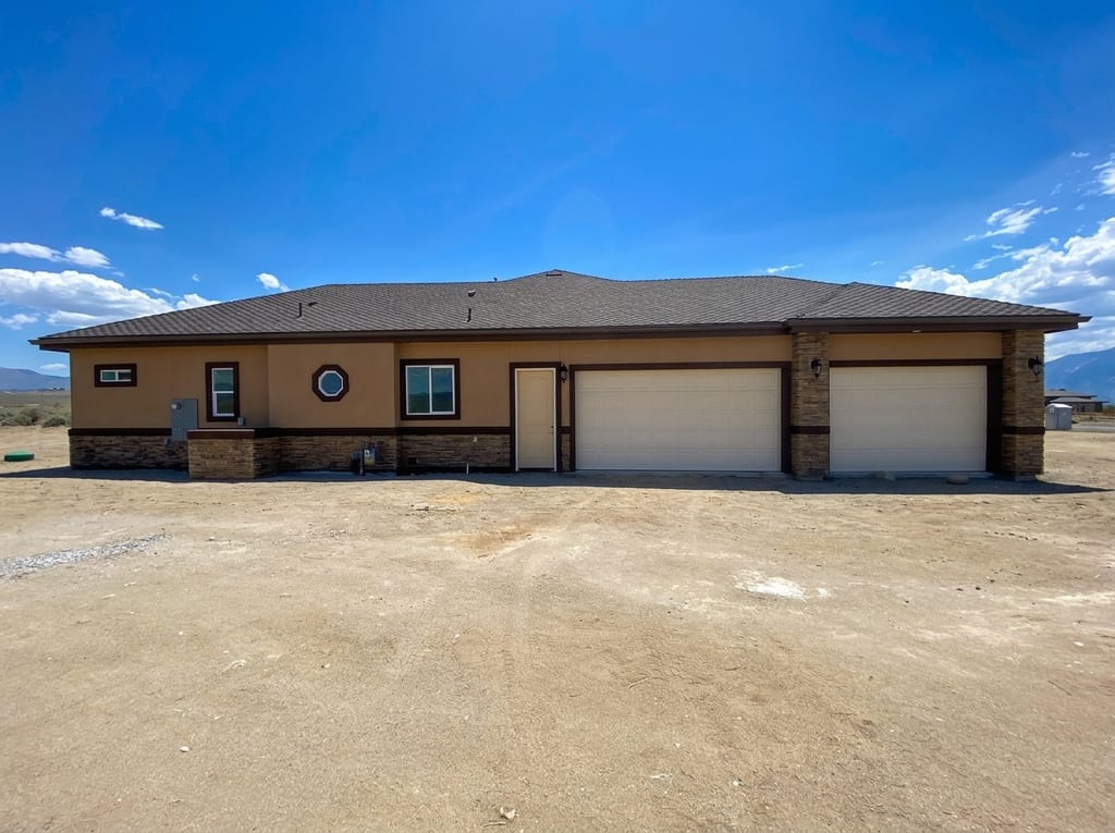 Custom built house in Minden: Completed two-car garage elevation with stacked stone wainscot and craftsman trim