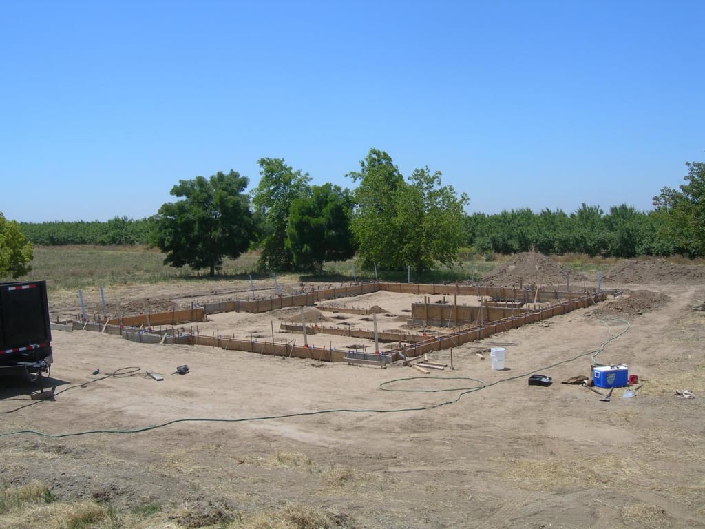 Chowchilla custom home foundation and groundwork: Laying moisture vapor barrier and tying steel rebar reinforcement