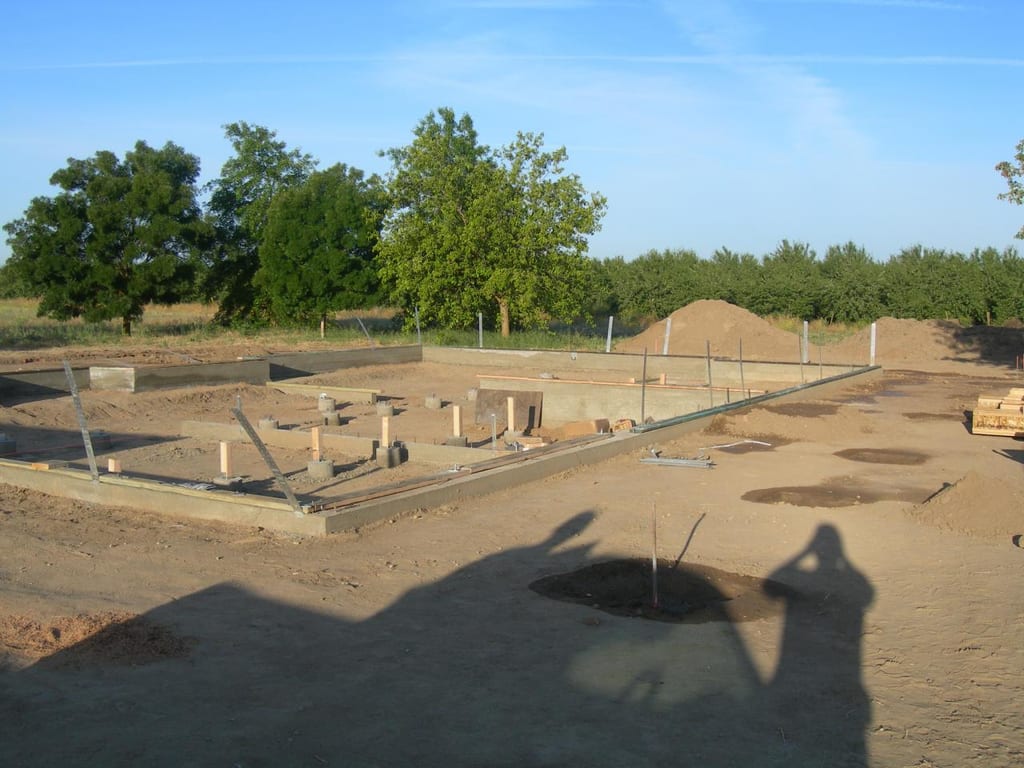 Chowchilla custom home foundation and groundwork: Pumping concrete into foundation footings and screeding slab surface