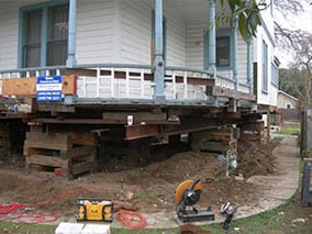 Historic brick home supported on steel I-beams and timber cribbing during foundation replacement